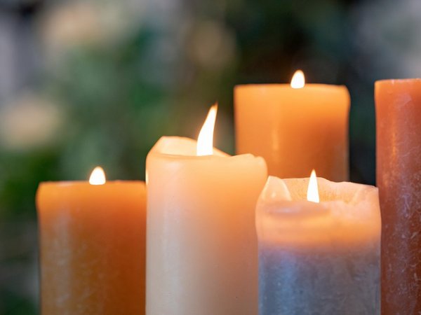 Mehrere brennende Kerzen stehen nebeneinander.