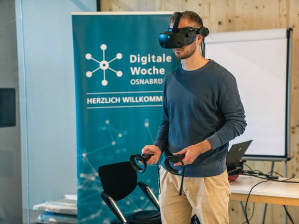 Person mit VR-Brille vor Roll up der Digitalen Woche.