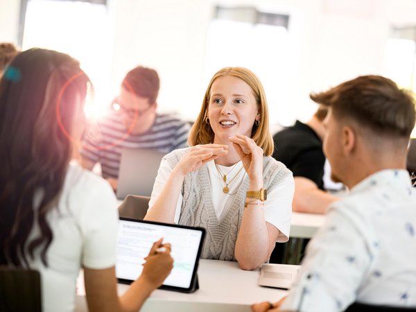 Drei Studenten sitzen an einem Tisch und reden