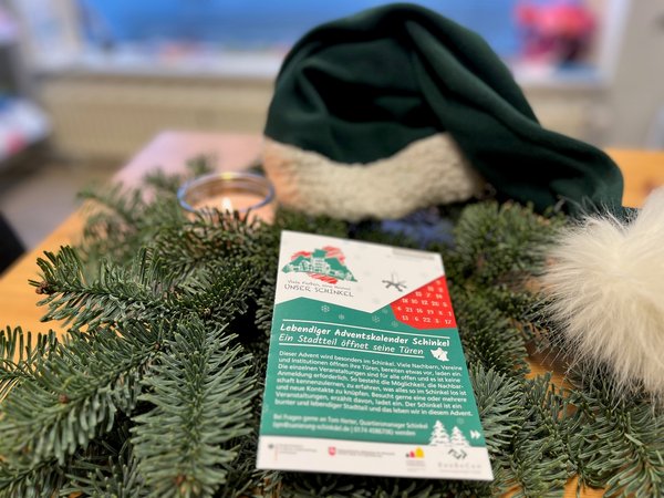 Flyer "Adventskaleender Schinkel" liegt auf weihnachtlich dekoriertem Tisch. 